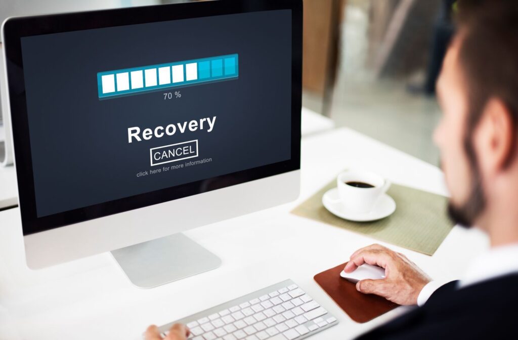 Profissional acompanhando processo de backup e recuperação de dados em computador corporativo.
