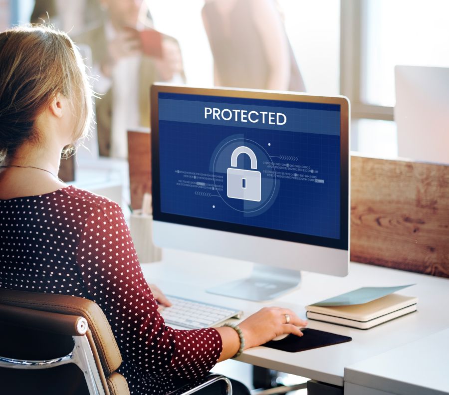 Mulher trabalhando em computador com ícone de cadeado na tela, representando proteção de dados LGPD.