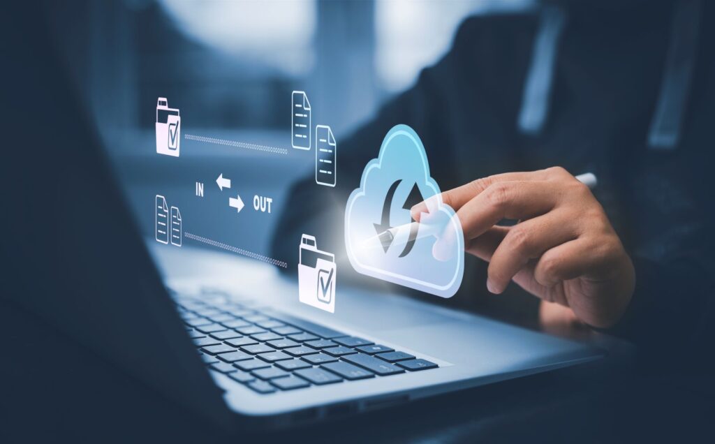 Profissional utiliza notebook com ícone de nuvem e arquivos representando backup automático de dados.